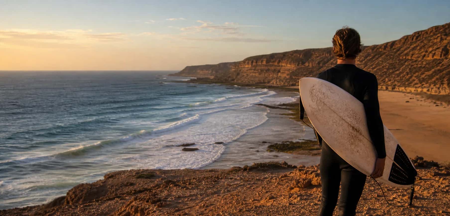 Surfer looking over Morocco's Atlantic coast at golden hour