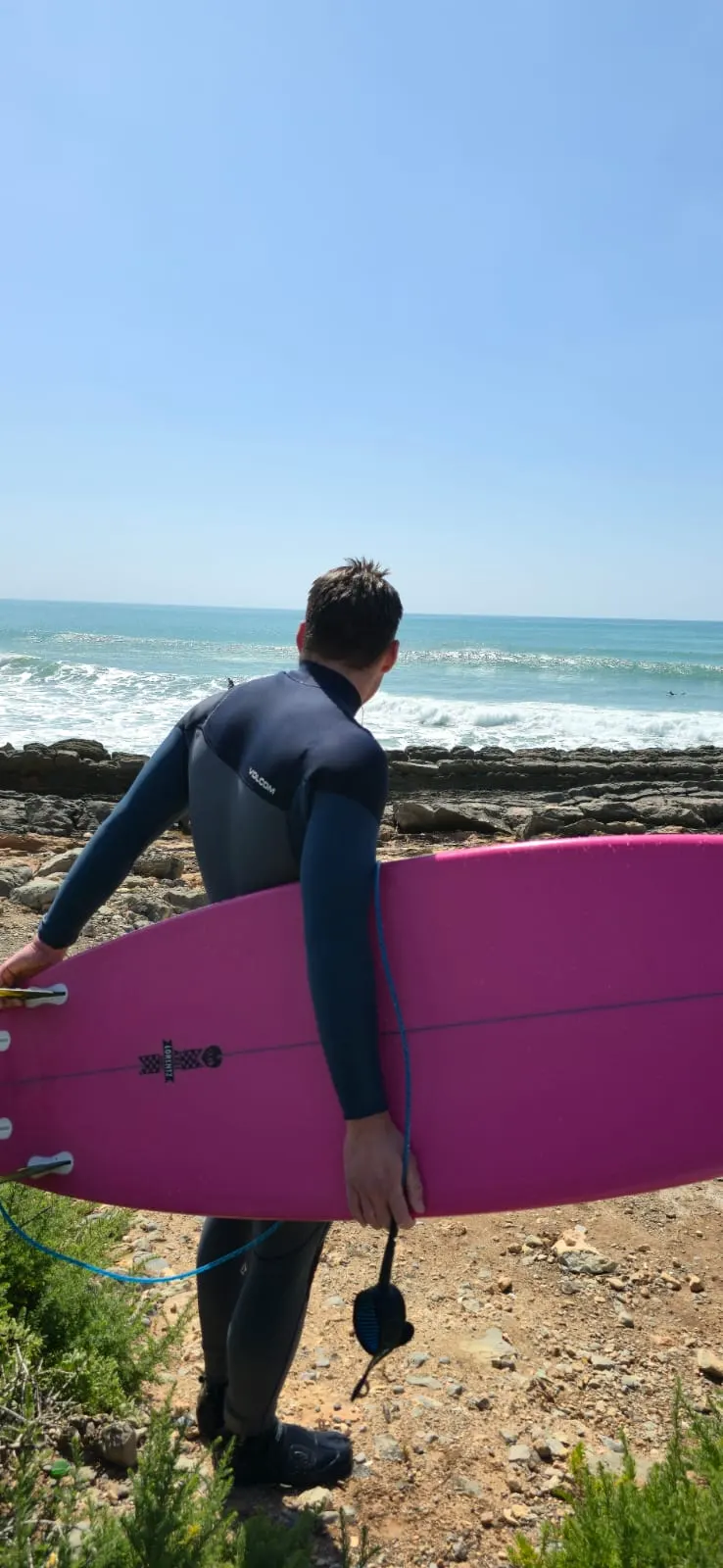Surfer standing on the rocks with a board on the Taghazout coast