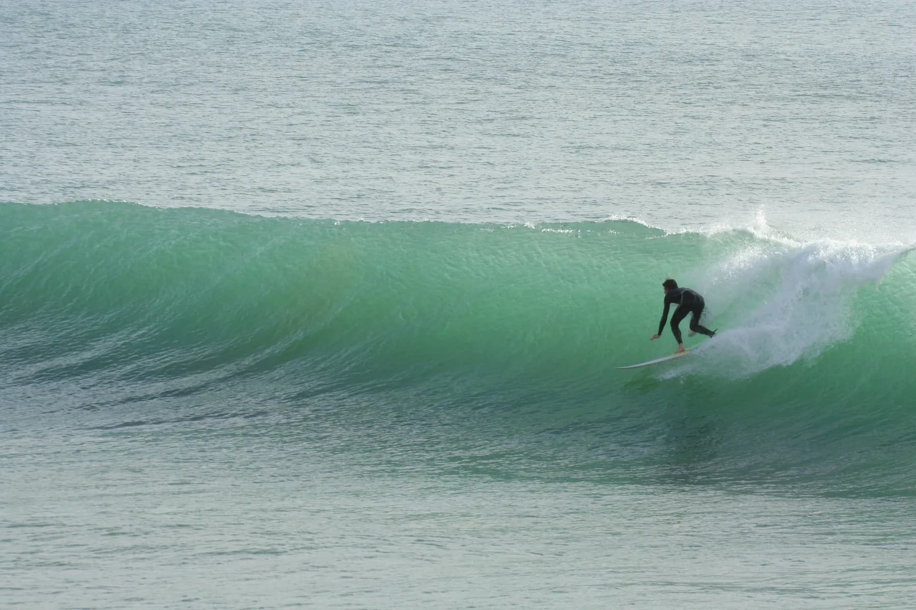 Surfer dropping into a green wave at Killer Point near Taghazout